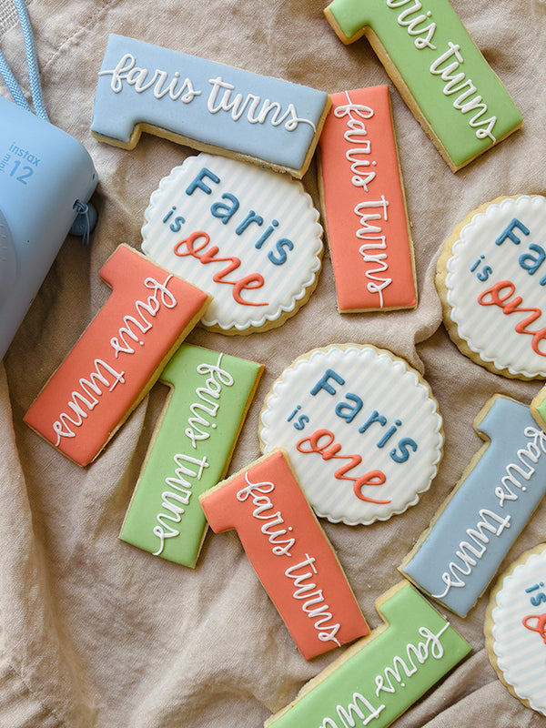 Hand-decorated cookies with personalized text for a first birthday