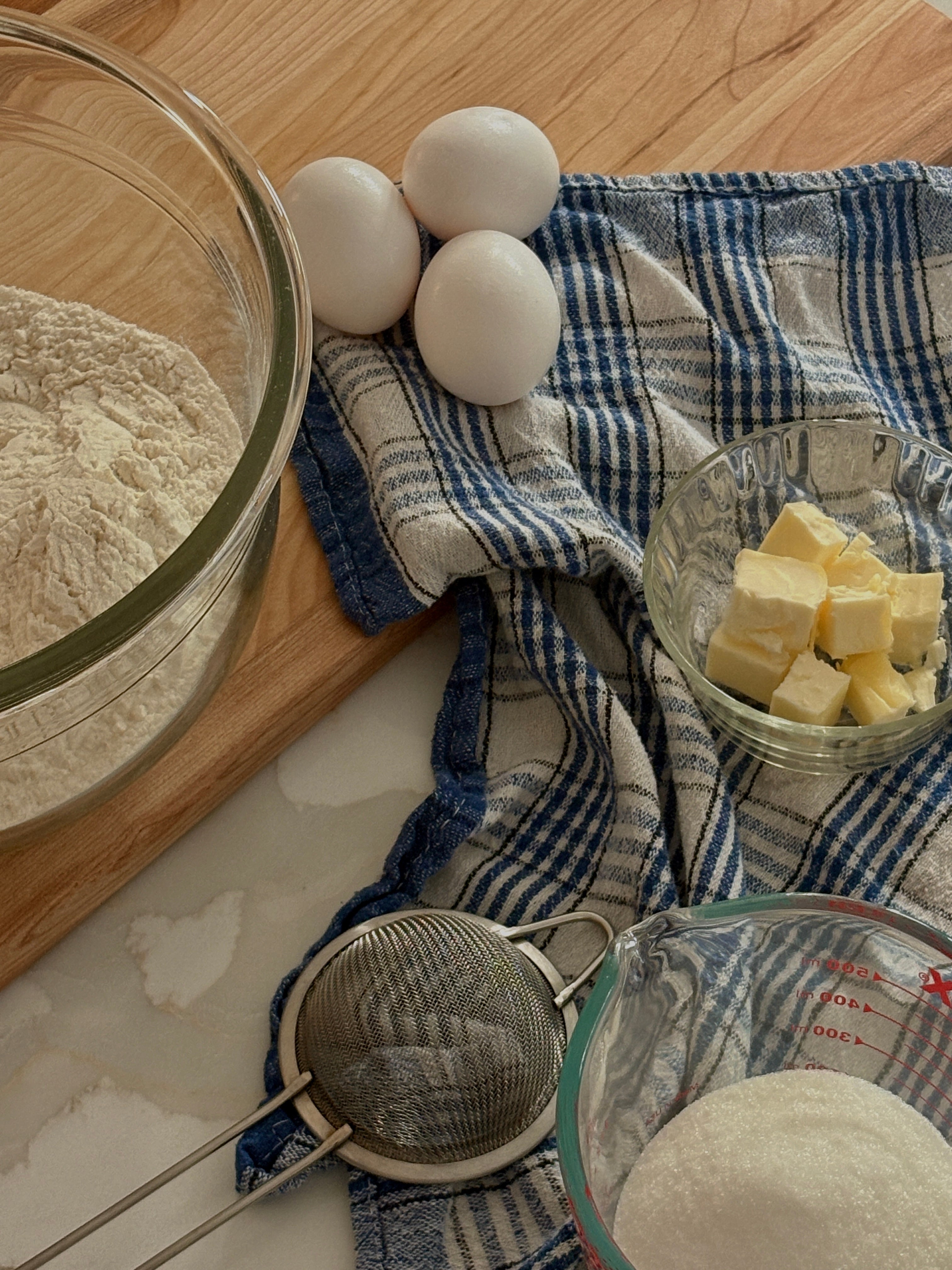 Bowl of flour, eggs, and cubed butter on a checkered cloth