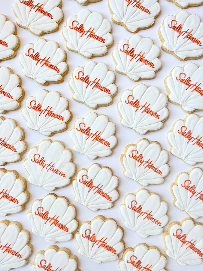 White seashell shaped cookies with hand written Sally Hansen in orange