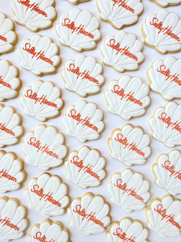 White seashell shaped cookies with hand written Sally Hansen in orange