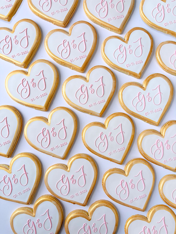 Heart shaped cookies with initials and wedding date written with icing