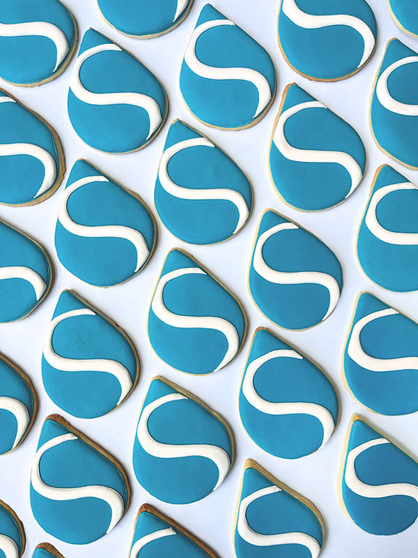 Teardrop shaped cookies with blue and white icing making the Skinvive logo